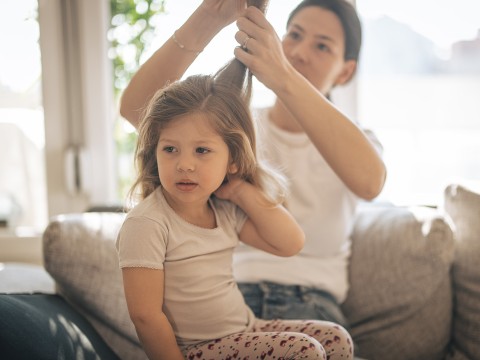Woman combing her child's hair and checking for head lice